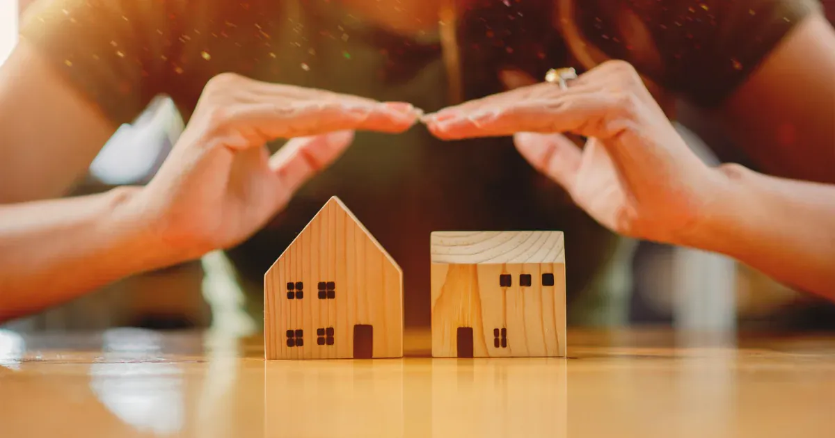 hands above wooden houses representing hidden costs of buying a home in the uk