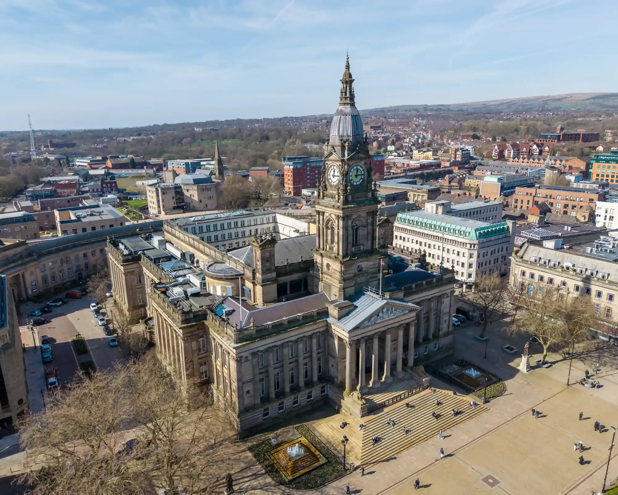 Bolton Town Hall with its domed clock tower and columned entrance overlooking Victoria Square, with the town and the West Pennine Moors behind.