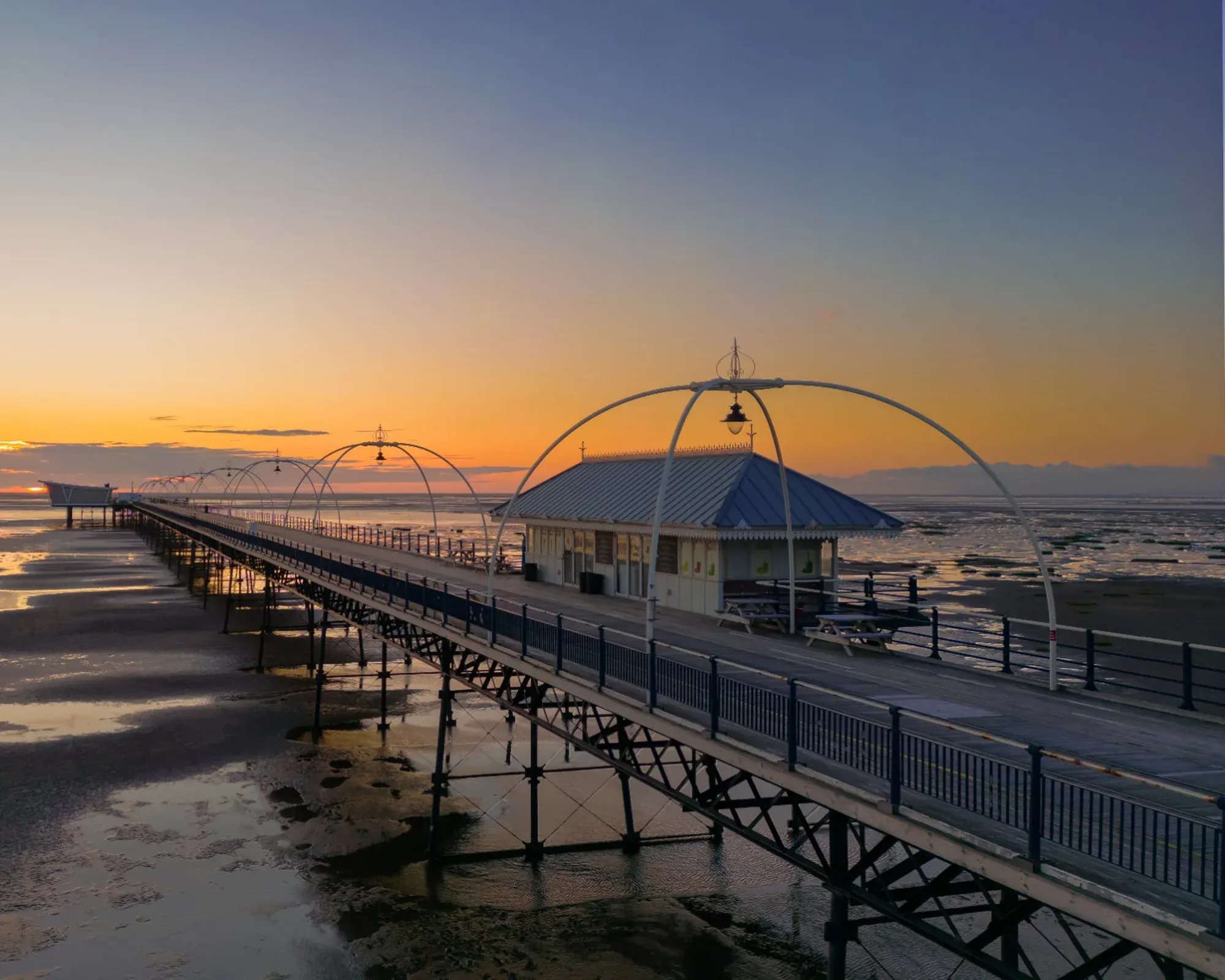 Southport Pier stretching out over the sands at sunset, with its Victorian lamp arches and pier-head pavilion.