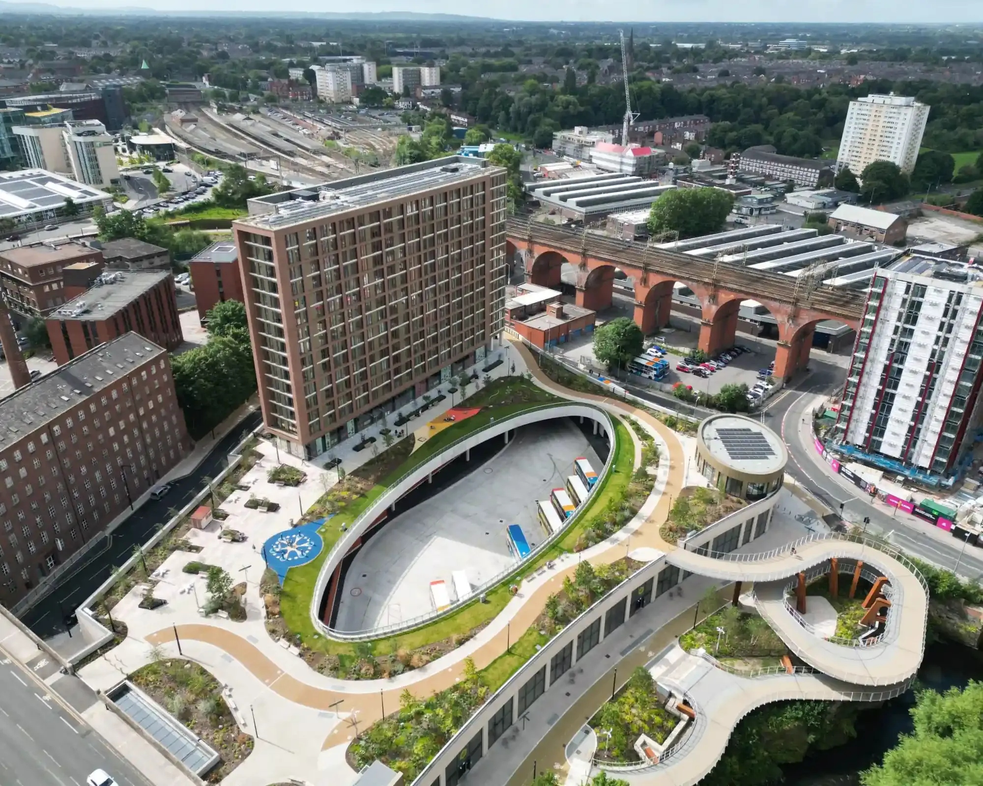 Aerial view of Stockport Interchange's rooftop park and apartment tower, with the red-brick Stockport Viaduct and town centre beyond.