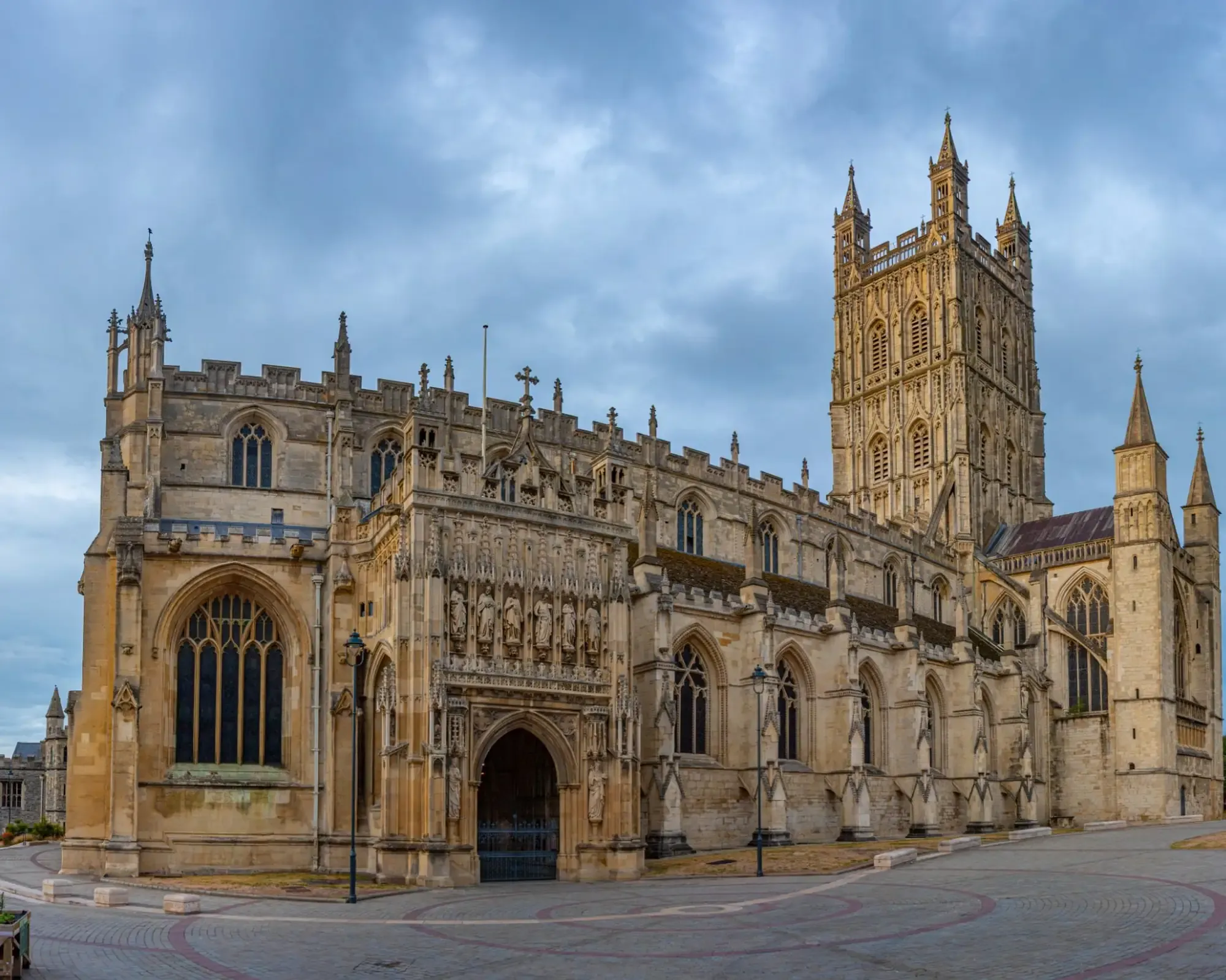 Gloucester Cathedral’s carved south porch and tower under a cloudy sky.