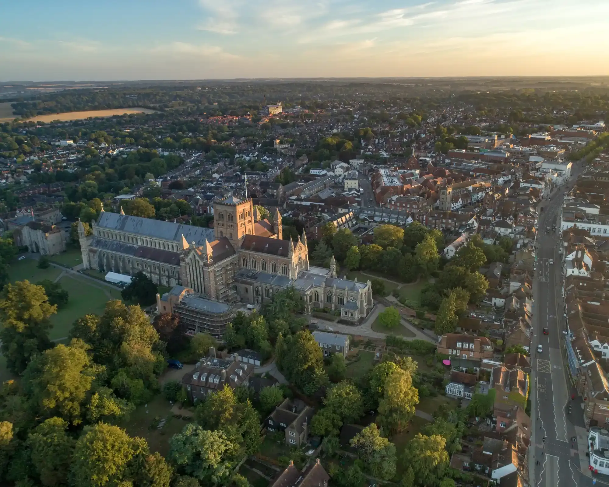 Aerial view of St Albans Cathedral at sunset, with the city centre and Hertfordshire countryside beyond.